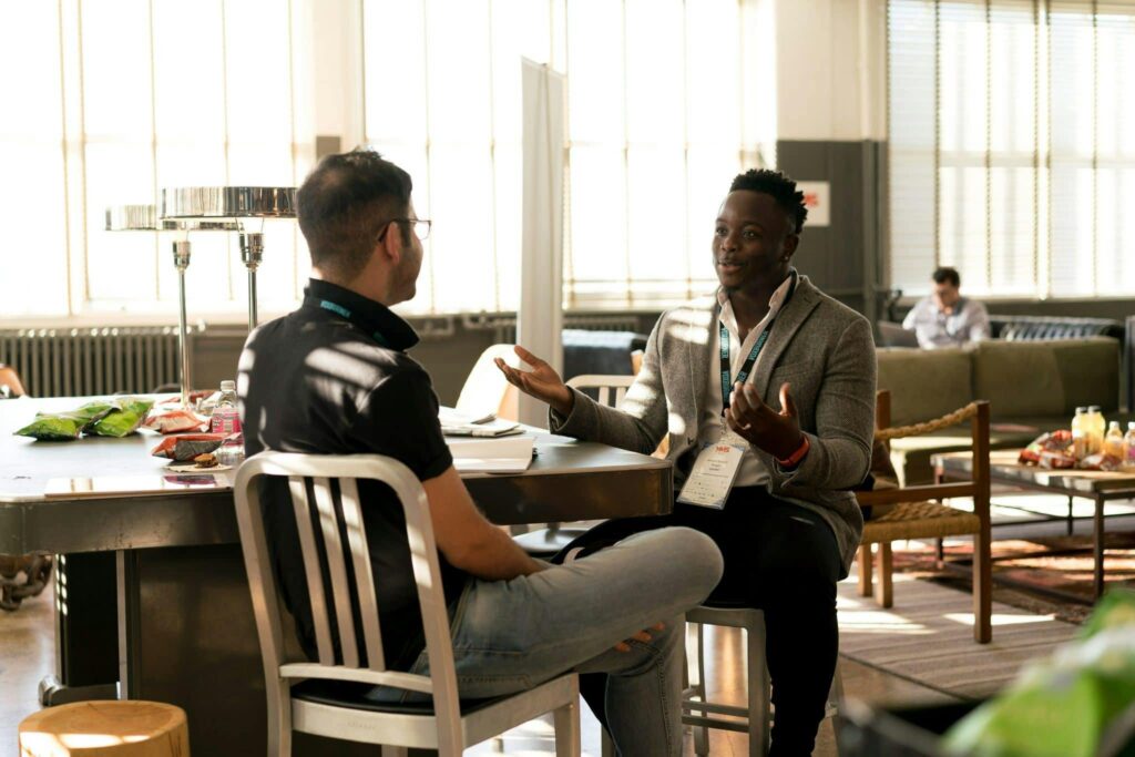 pexels-photo-935949-935949 Two men having a casual discussion in a bright indoor setting, highlighting mentorship.